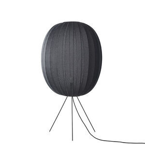 Oval sort gulvlampe med strikket overflade og tynde ben.